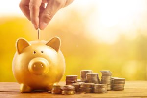 a person putting a coin into a piggy bank.